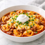 Beef enchilada tortellini in a white bowl with melted cheese and cilantro