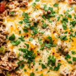 Mexican beef and rice skillet with melted cheese and cilantro in a cast iron pan