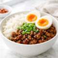 Spicy ground beef stir fry bowl with rice, sesame seeds and green onions