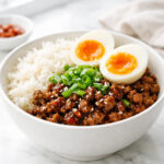 Spicy ground beef stir fry bowl with rice, sesame seeds and green onions