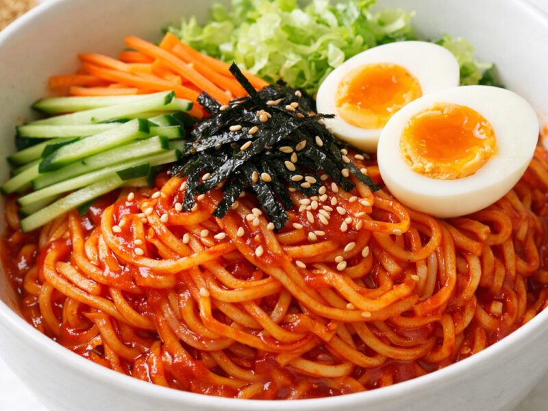 Bowl of Korean bibimmyeon with colorful vegetables and soft-boiled egg