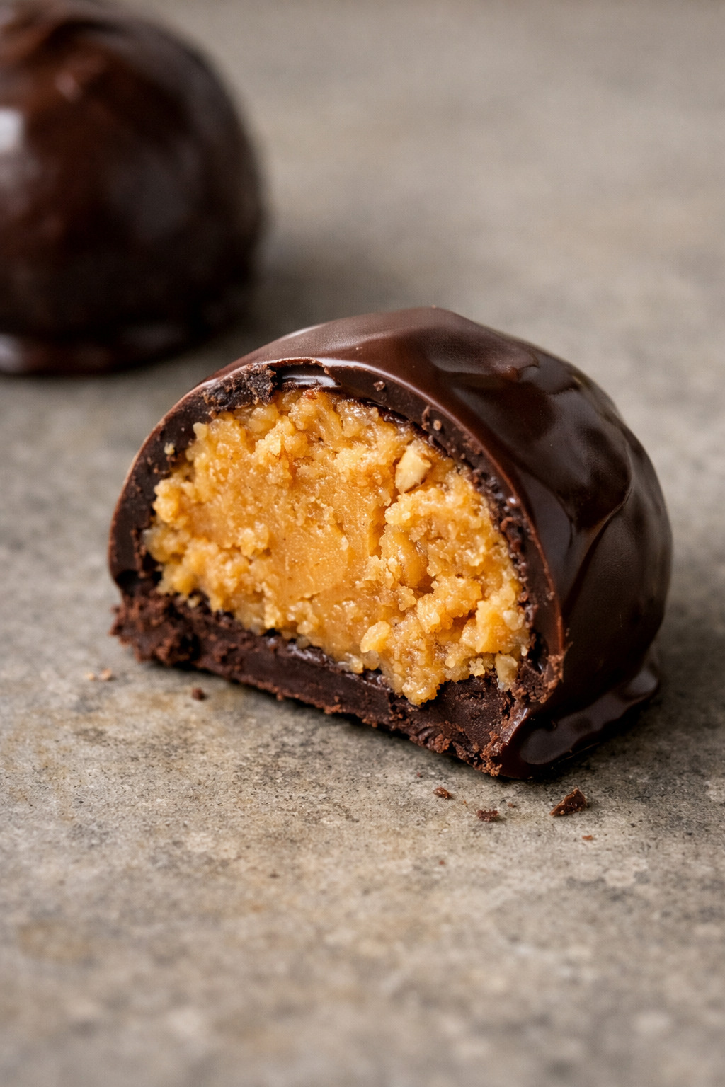 Closeup of chocolate peanut butter ball cut in half showing peanut butter center