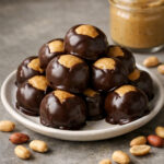Chocolate covered peanut butter balls piled on a white plate