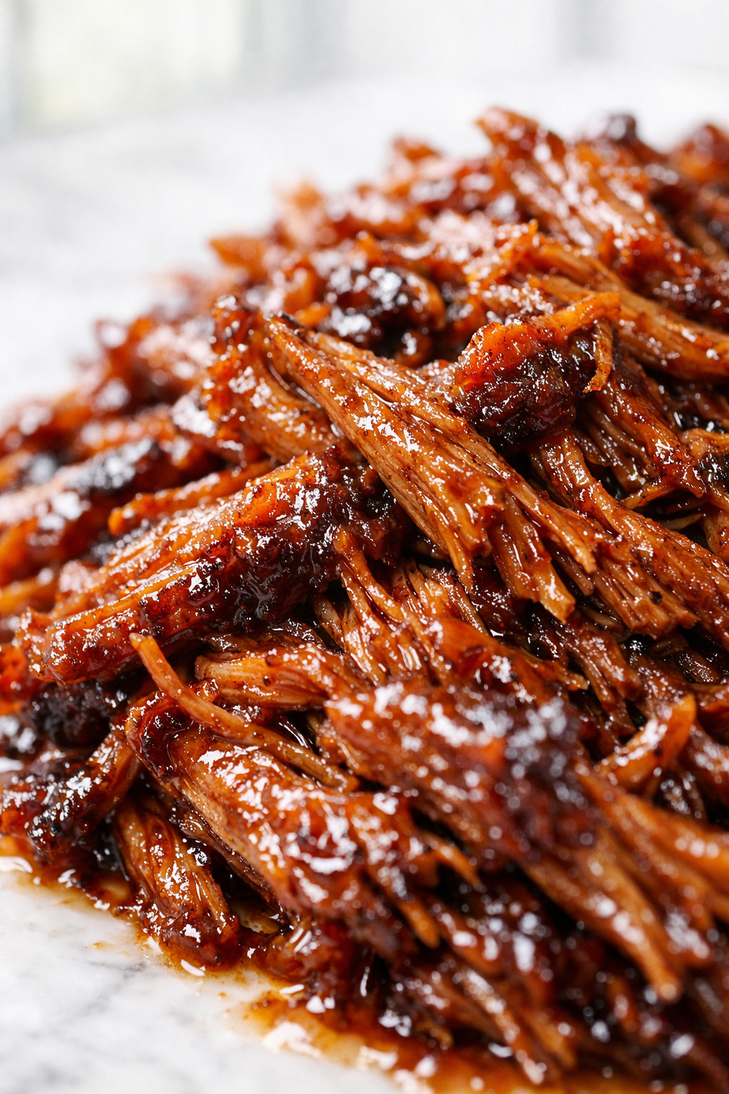 Close up of tender shredded coca cola pulled pork with glossy glaze