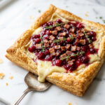Cranberry brie tart with crispy pancetta and fresh thyme on golden puff pastry
