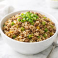 Bowl of dirty rice with ground beef garnished with green onions