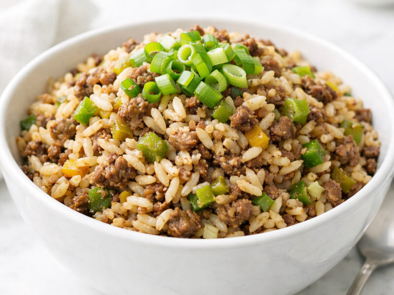 Bowl of dirty rice with ground beef garnished with green onions