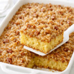 Do nothing cake in white ceramic baking dish with coconut pecan topping