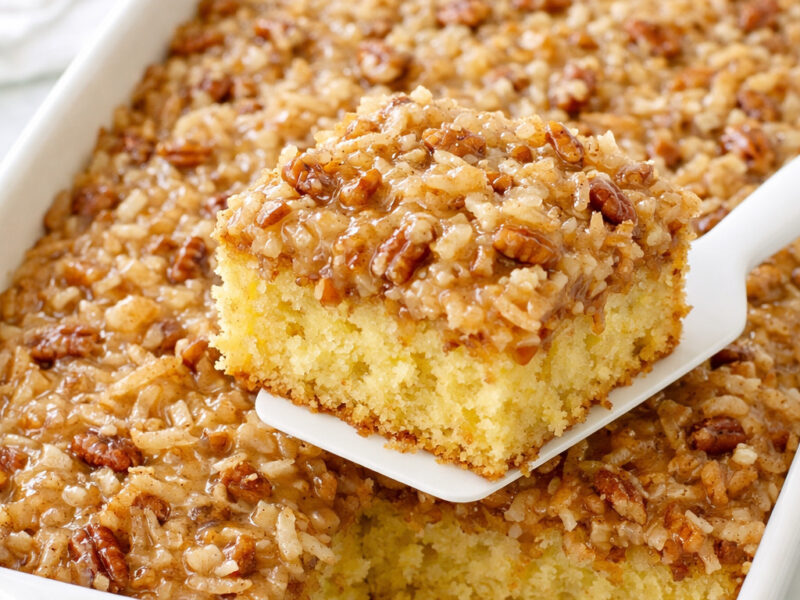 Do nothing cake in white ceramic baking dish with coconut pecan topping