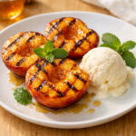 Grilled peaches on white plate with honey and vanilla ice cream