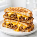 Cheesy ground beef melt sandwich cut in half showing melted cheese and seasoned beef