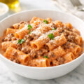 Ground beef pasta with creamy tomato sauce and parmesan in a white bowl