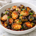 Honey sriracha Brussels sprouts in a white bowl on a marble surface