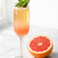 Mint grapefruit mimosa in a champagne flute with fresh mint garnish