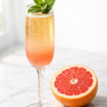 Mint grapefruit mimosa in a champagne flute with fresh mint garnish