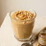 Creamy peanut butter pudding in a glass dessert cup topped with whipped cream and crushed peanuts