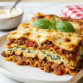 Freshly baked ragu lasagna with golden brown cheese in white ceramic dish