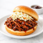 Root beer pulled pork sandwich on a brioche bun with coleslaw
