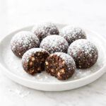 Rum balls coated in powdered sugar on a white ceramic plate