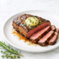 Pan-seared sirloin tip steak with garlic herb butter on a white plate
