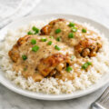 Golden seared chicken thighs smothered in creamy gravy served over white rice