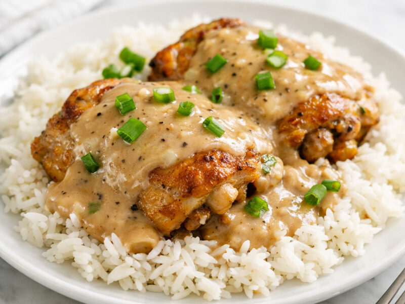 Golden seared chicken thighs smothered in creamy gravy served over white rice