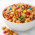 Sweet Chex mix in a white bowl with golden caramel coating