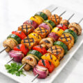 Grilled vegan kebabs with colorful vegetables and tofu on a white plate