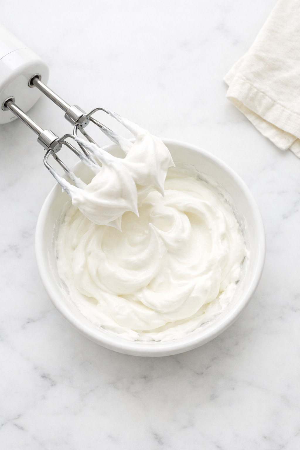 Electric mixer whipping cream showing soft peaks
