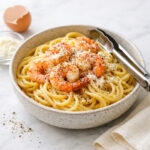 Shrimp carbonara in a stoneware bowl with pecorino and black pepper